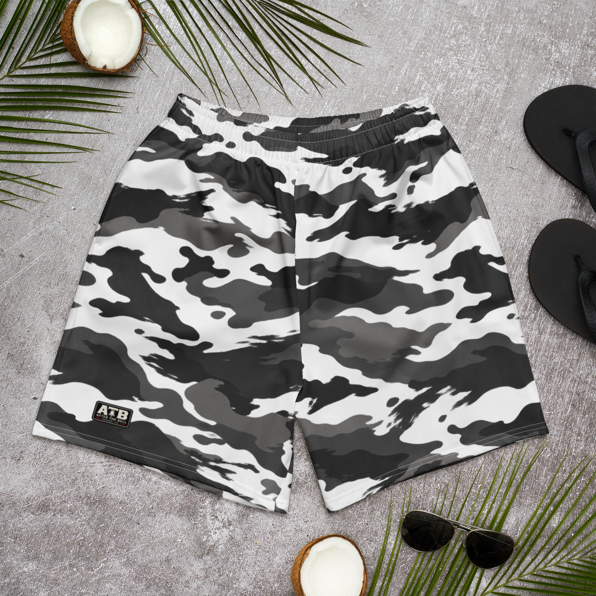 Front view of white, charcoal and black camouflage athletic shorts with a small ATB logo, laid flat on a gray surface.