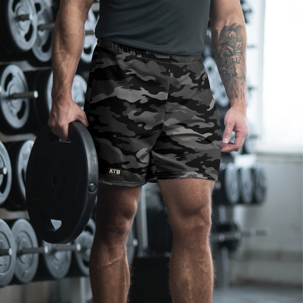 Man wearing black camouflage athletic shorts and a dark workout shirt in a gym.