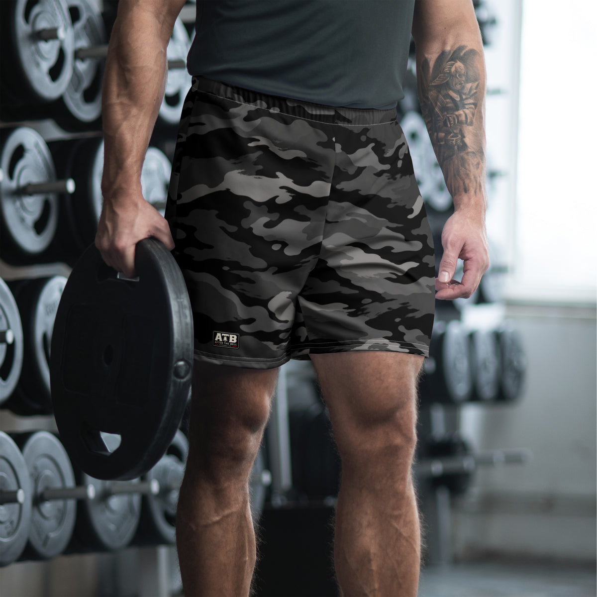 Man wearing black camouflage athletic shorts and a dark workout shirt in a gym.
