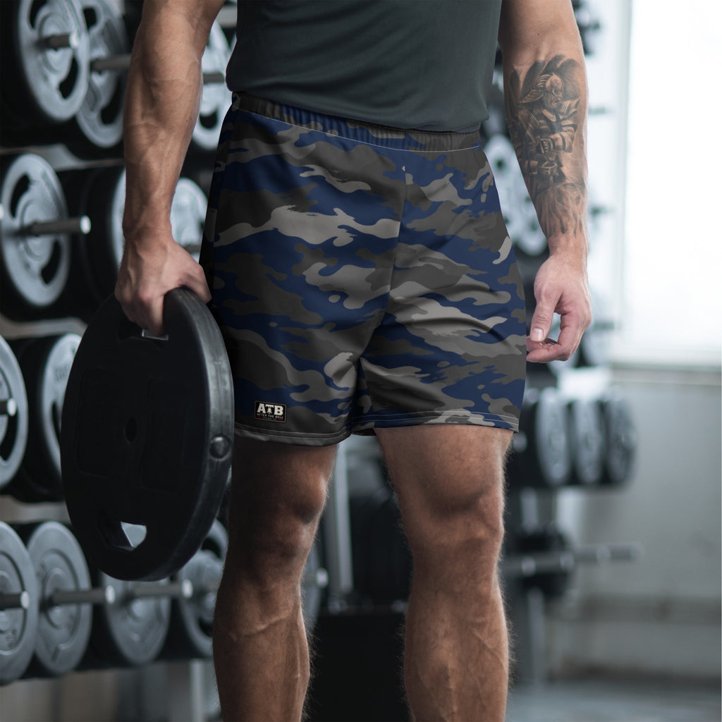 Man wearing navy camouflage athletic shorts and a dark workout shirt in a gym.