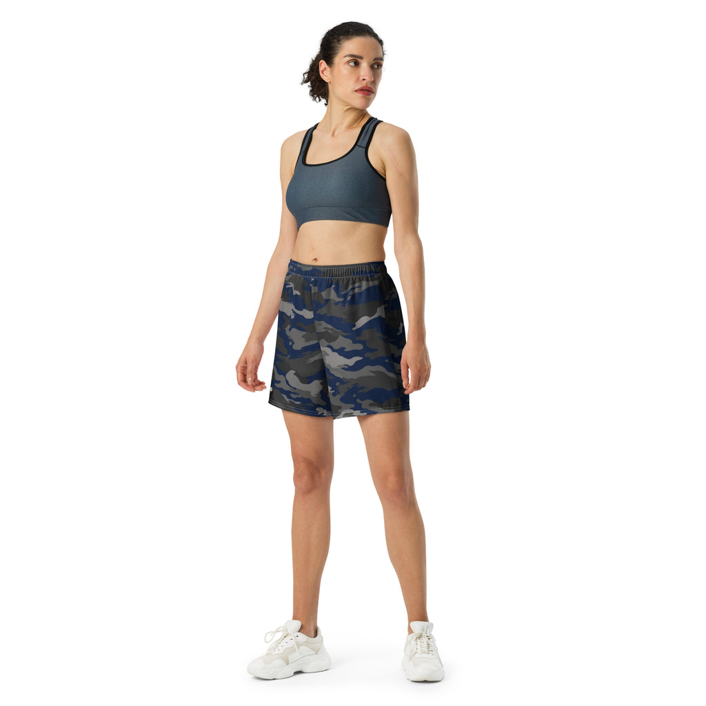 Woman wearing navy camouflage athletic shorts with a dark sports bra and white sneakers.