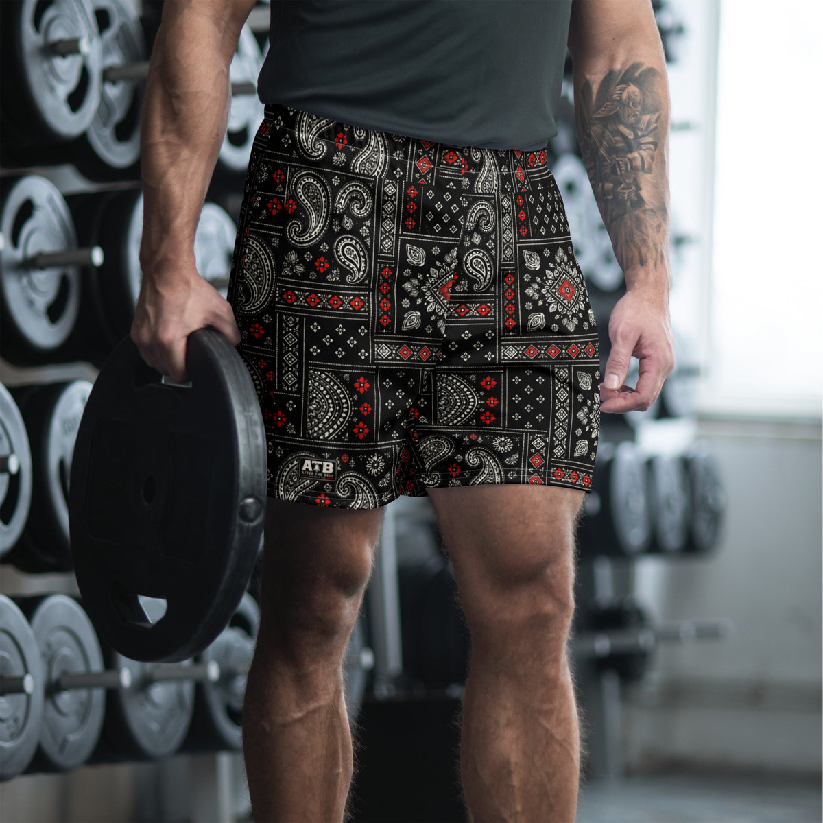 Man wearing black bandana-print athletic shorts and a dark workout shirt in a gym.