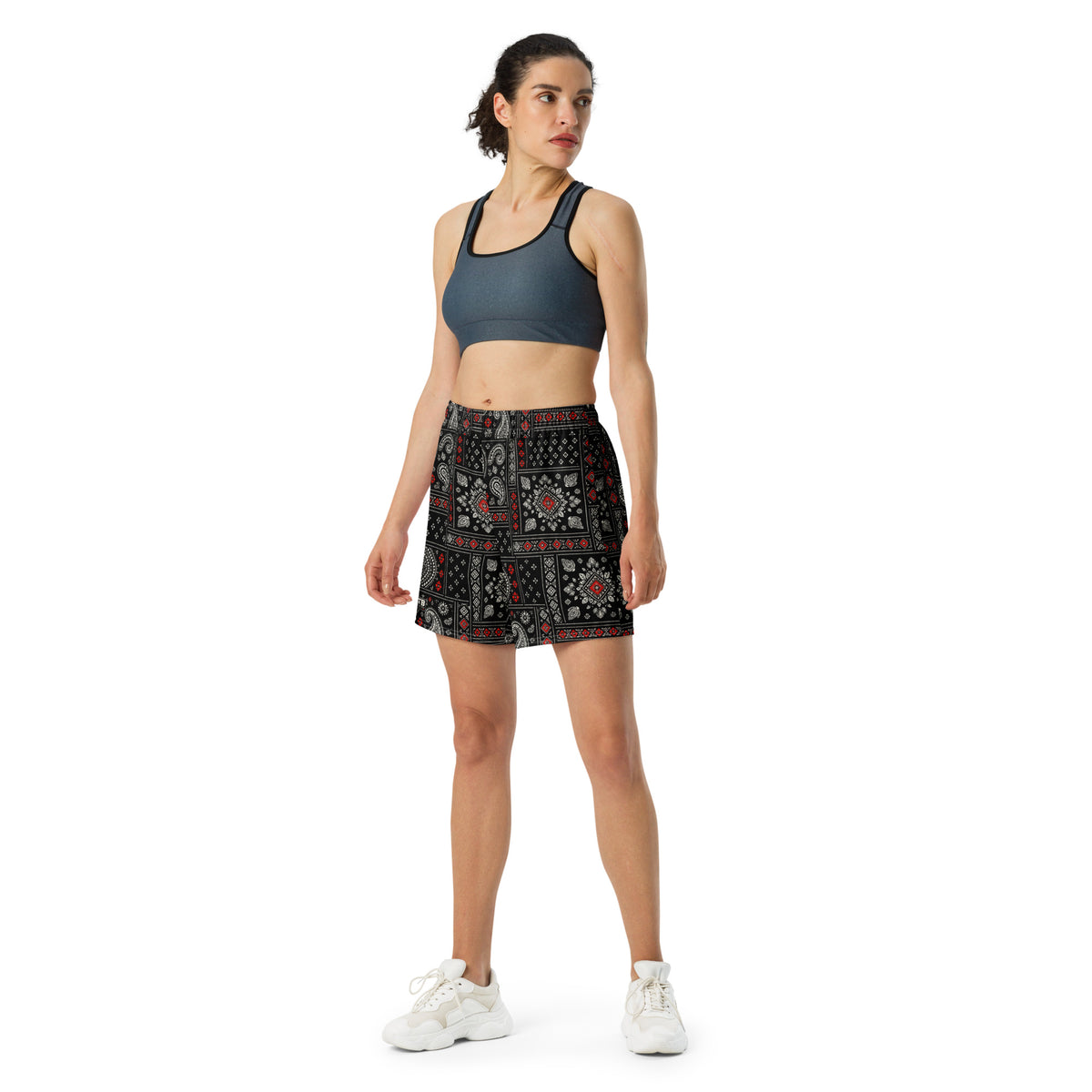 Woman wearing black bandana-print athletic shorts with a dark sports bra and white sneakers.