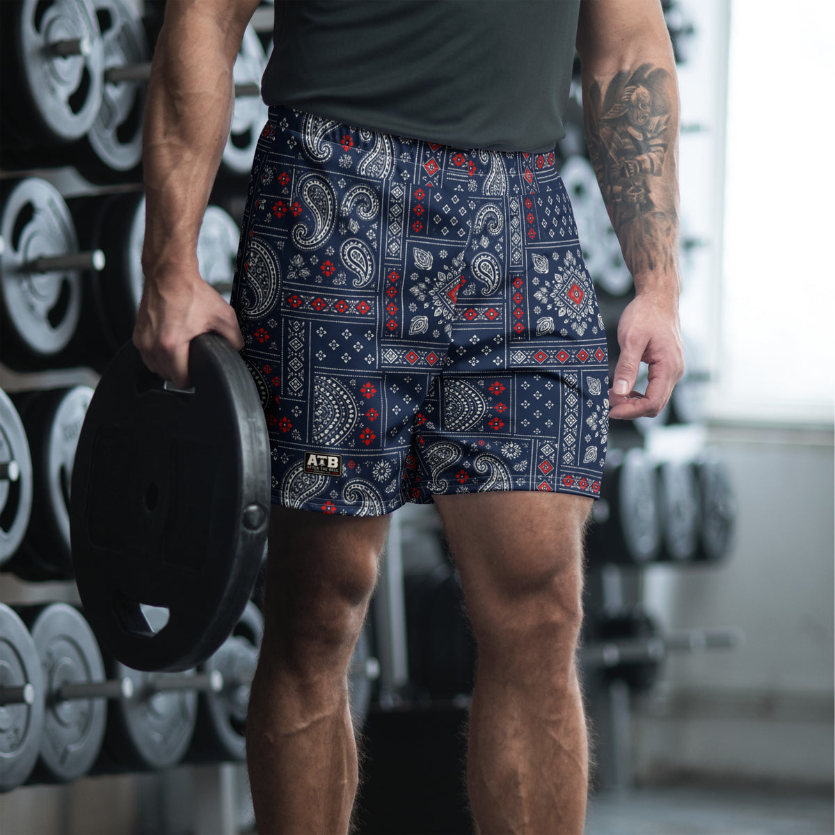 Man wearing navy bandana-print athletic shorts and a dark workout shirt in a gym.