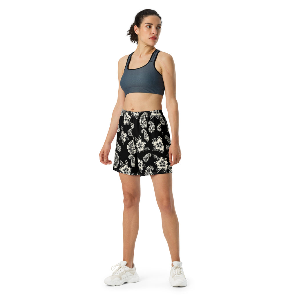Woman wearing black floral and paisley athletic shorts with a dark sports bra and white sneakers.